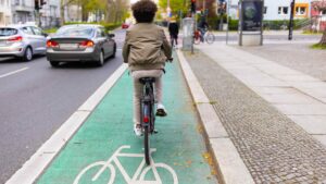 boy riding bicycle in bicycle lane in traffic