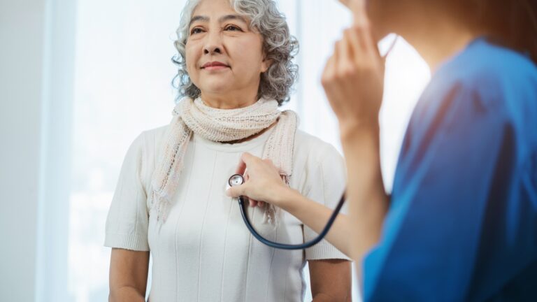 senior woman at doctor appointment with doctor listening to her heart