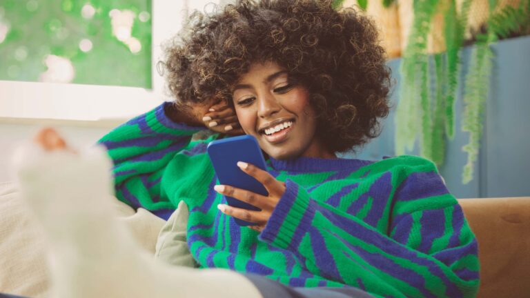young african american woman smiling looking at her phone