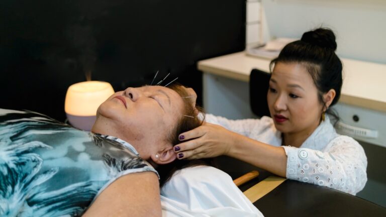 senior aged woman receiving acupuncture treatment in her forehead
