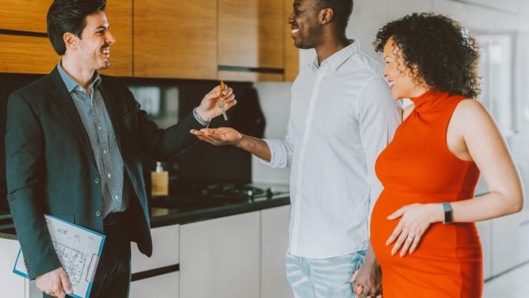 pregnant woman and husband getting key from realtor to new house