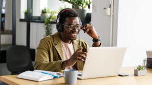 happy young African-American man working at his laptop with headset on