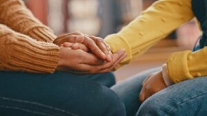 close-up of two women's hands in consoling hand-hold.