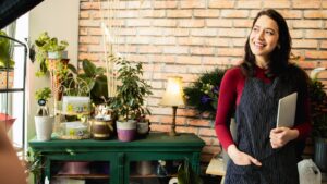 female small business owner holding clipboard deep in thought